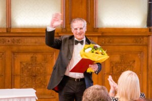 Professor Reinhard Wallner mit Blumenstrauss und Urkunde im Palais Niederösterreich nach der Verleihung des Ehrentitels