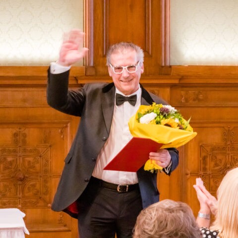 Professor Reinhard Wallner mit Blumenstrauss und Urkunde im Palais Niederösterreich nach der Verleihung des Ehrentitels
